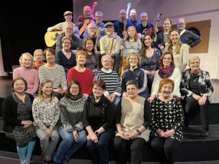 Ryhmä miehiä ja naisia istumassa.