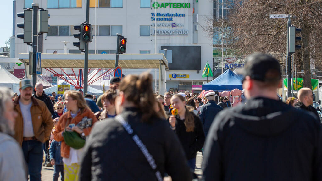 Ihmisiä kävelemässä Valkeakosken keskustassa vappuna ja odottamassa liikennevaloissa.
