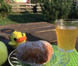 Pöydällä on keltainen tipu, munkkilautanen ja lasi simaa.