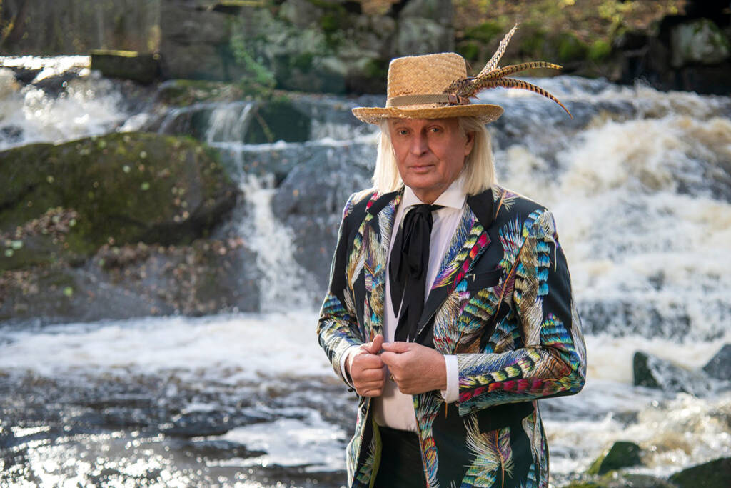 Muotitaiteilija Jukka Rintalan henkilökuva ja taustalla vesiputous.