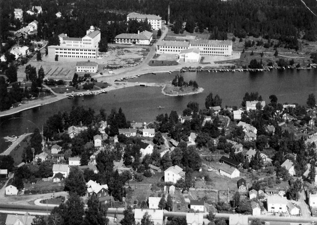 Vanha mustavalkoinen kuva, jossa Pässinmäen omakotialuetta ja taustalla yhteiskoulu, ammattikoulu, seurakuntatalo sekä sairaala.