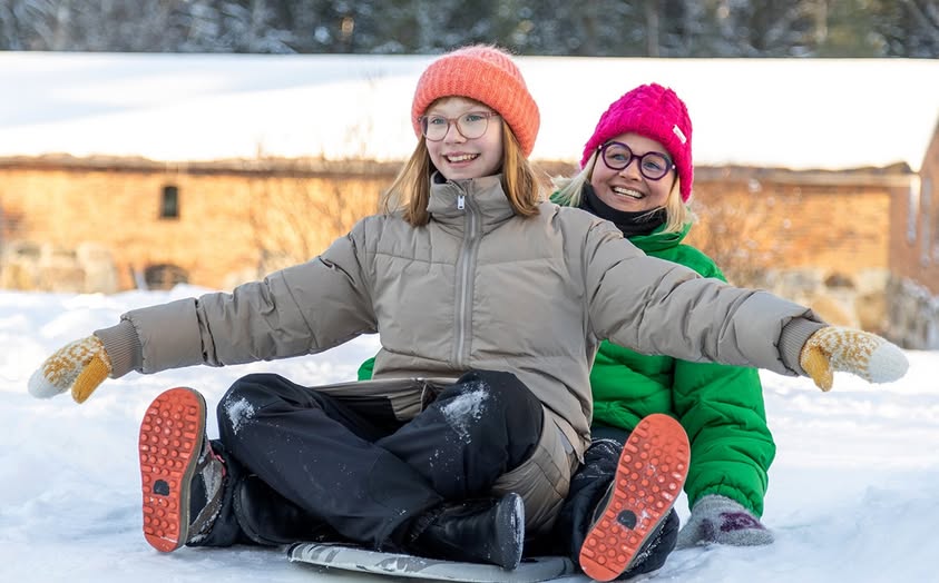 Aikuinen ja lapsi laskevat pulkalla yhdessä.