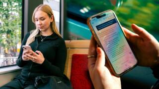 Kuvassa nainen istuu ikkunan vieressä ja katsoo puhelintaan, vieressä on lähikuva hänen kädestään, joka pitelee puhelinta.